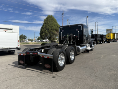 Peterbilt 389 conventional sleeper tractor from rear-side angle showing dual rear axles, fifth wheel, and black exhaust stacks.