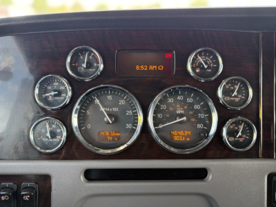 Peterbilt 389 dashboard cluster showing multiple gauges and digital clock, with woodgrain panel.