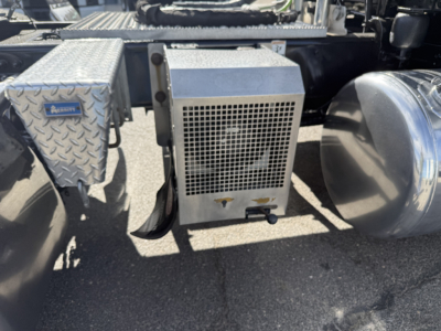 Peterbilt 389 truck undercarriage showing auxiliary air filter housing and metal toolbox with diamond plate pattern.