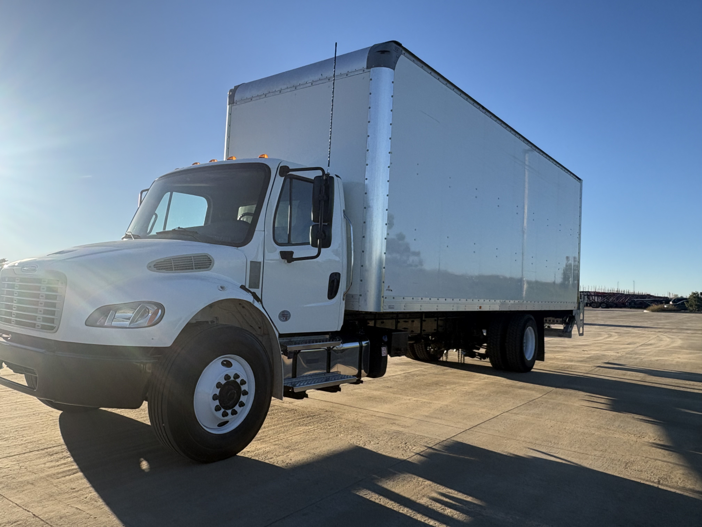Freightliner M2-106 box truck side view showing cargo box and front cab with white exterior.