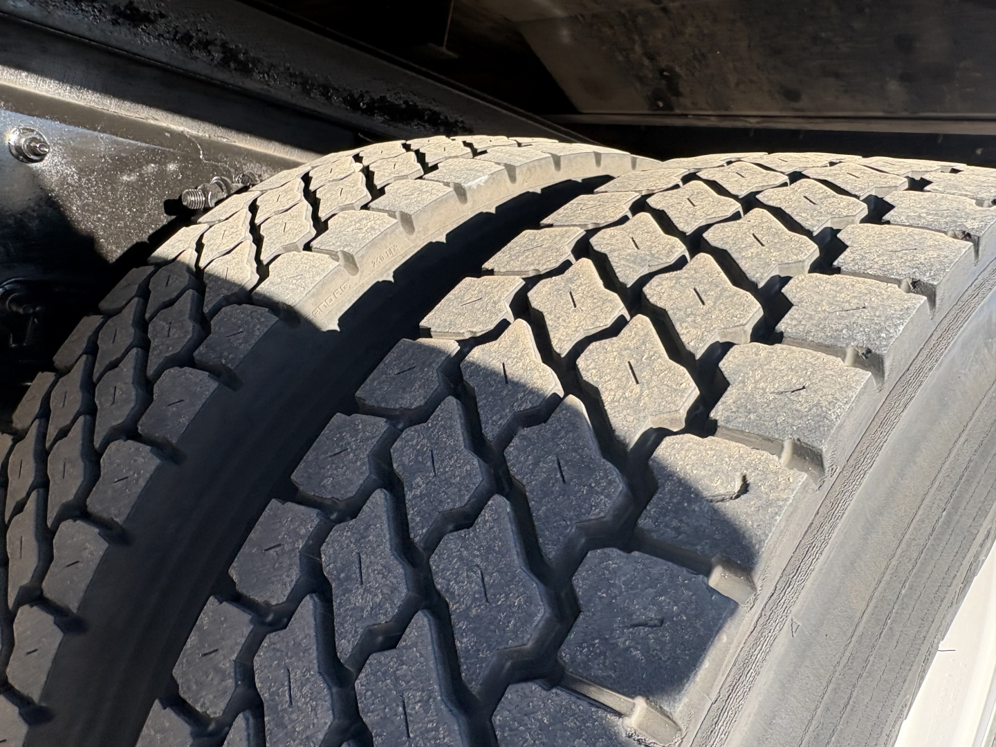 Front wheel and tire of a Freightliner M2-106 truck showing tread pattern in service condition.