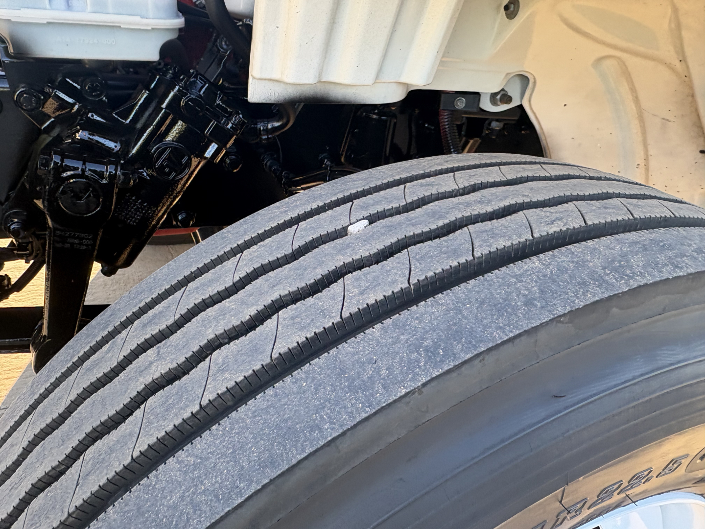 Freightliner M2-106 front wheel well and tire with engine bay components visible. No text clearly legible other than partial vehicle labels