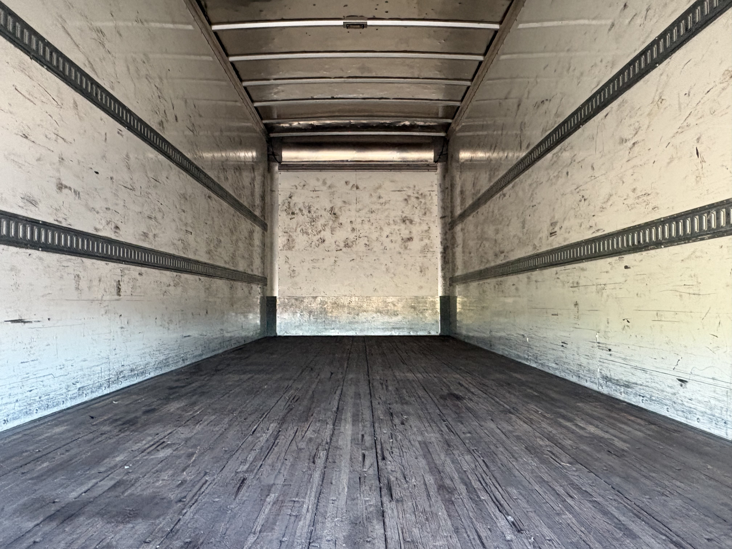 Freightliner M2-106 truck trailer cargo area showing empty box bed with wood floor and sidewall E-track rails.