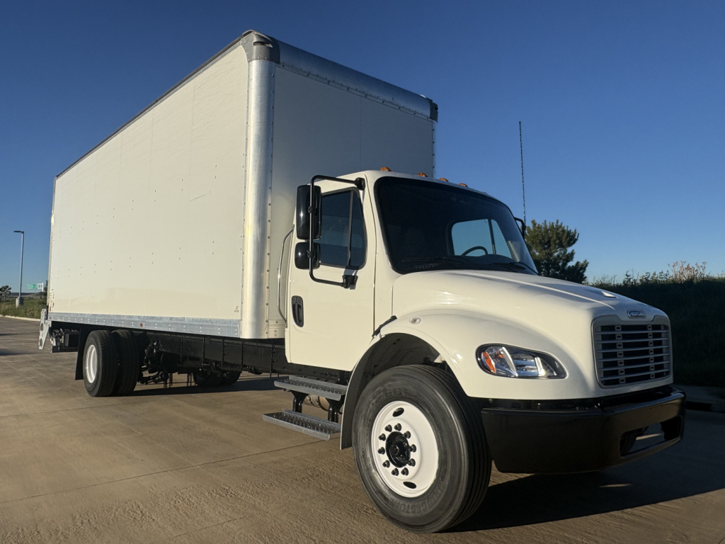 Freightliner M2-106 box truck side view showing large cargo box and front cab with white paint.