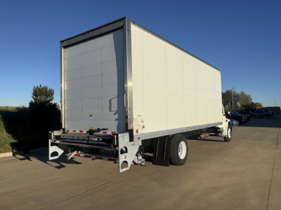 View of a Freightliner M2-106 box truck rear-left angle showing cargo box and rear doors, with bumper guard and wheel well.