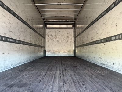 Empty Freightliner M2-106 box truck cargo area with wood floor and side E-track rails.