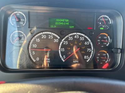 Dashboard of a Freightliner M2-106 showing analog gauges and a green digital odometer display reading 221549.0 miles, engine oil, water, battery, and pressure gauges visible.