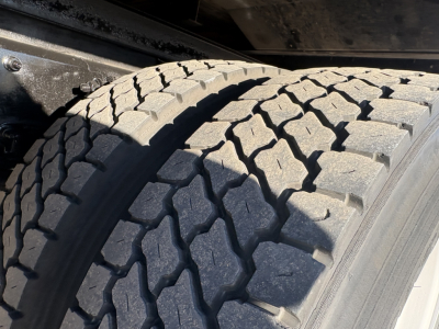 Front wheel and tire of a Freightliner M2-106 truck showing tread pattern in service condition.