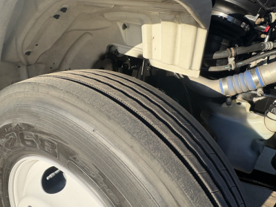 Freightliner M2-106 front wheel and engine bay view showing tire and suspension components.