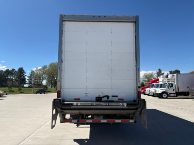 Freightliner M2-106 cargo truck rear view with roll-up door and bumper, visible stock and equipment area.
