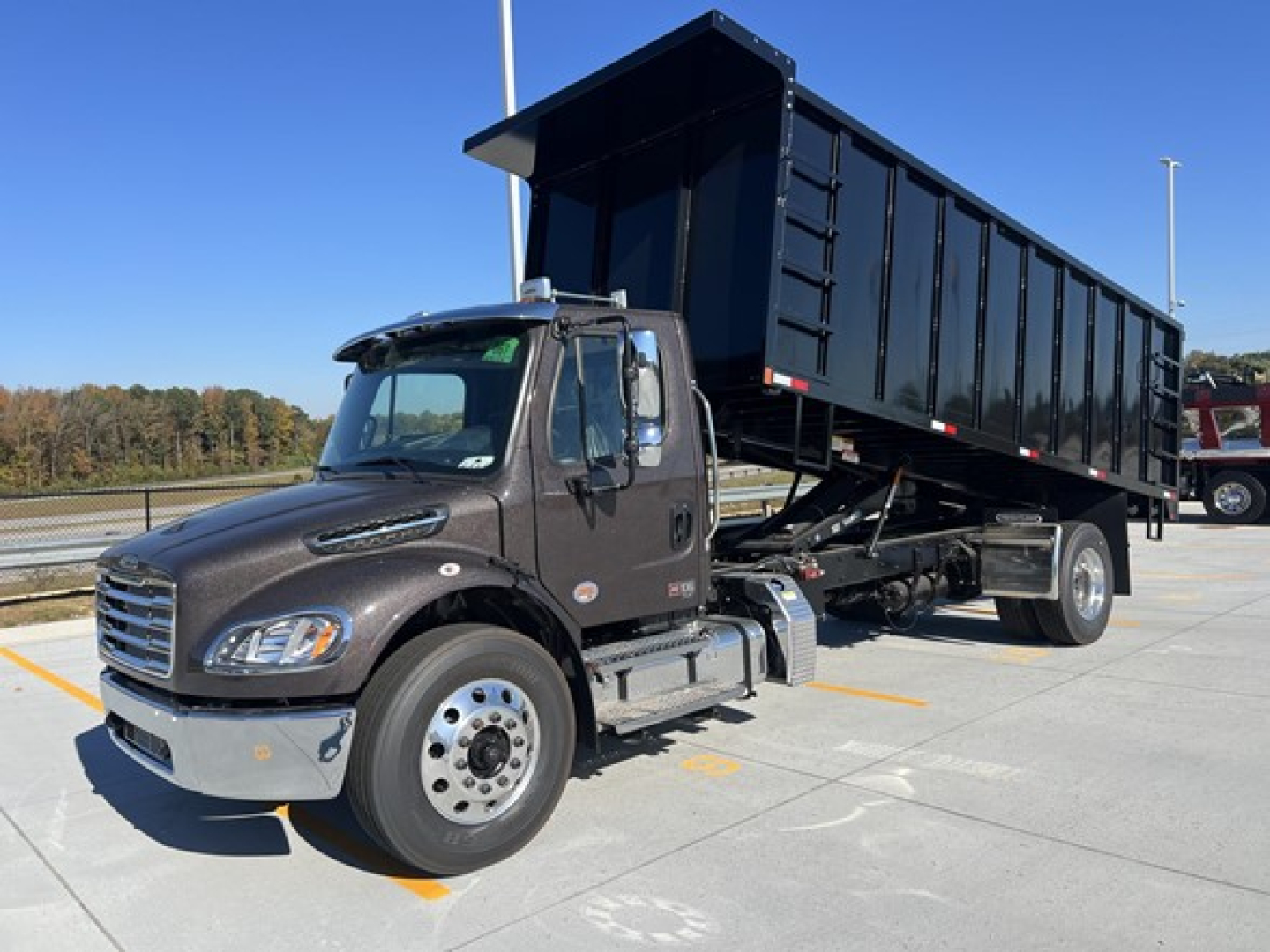 Freightliner M2 106 dump truck in service position with black dump body raised, cab view, VIN 1FVACWFC4THWP6154 visible on listing.