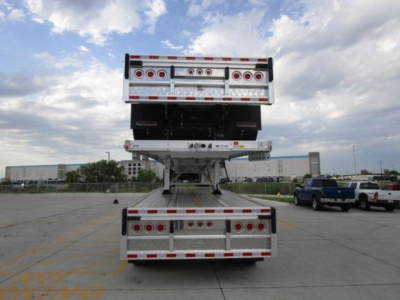 Reitnouer flatbed trailer stacked in yard with rear view showing multiple taillights and reflective striping.