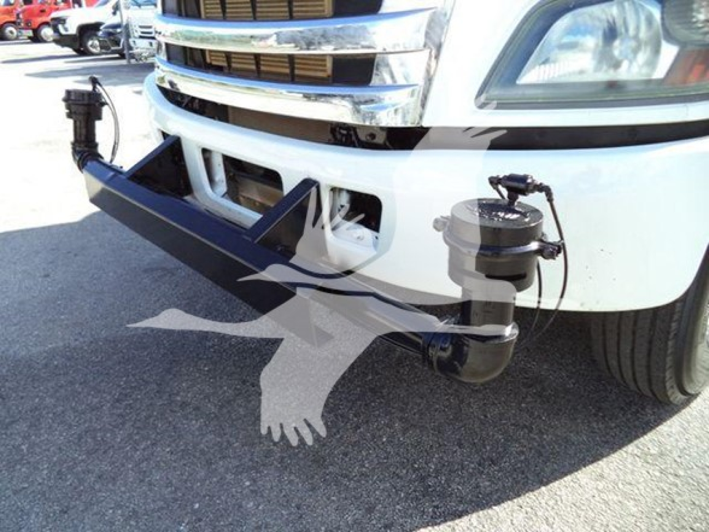 Front view of a 2019 Hino 338 truck showing a large bumper guard with attached hydraulic or air suspension components and piping visible near the bumper.