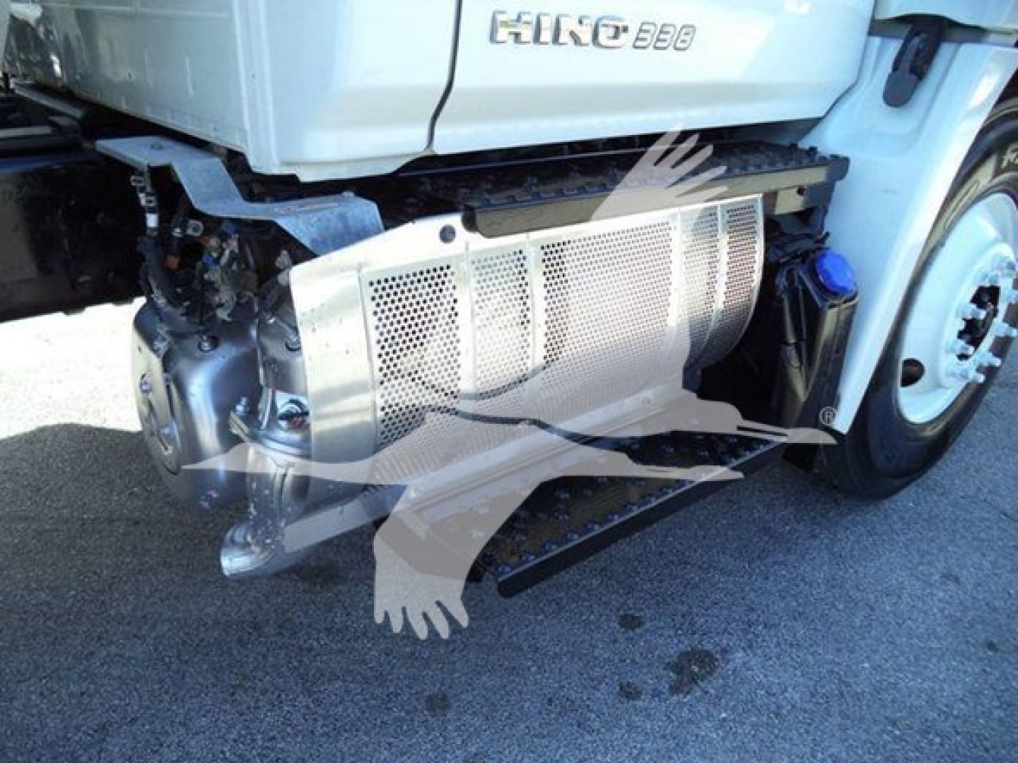Front lower side of a 2019 Hino 338 cab with protective radiator guard and exposed engine components visible.