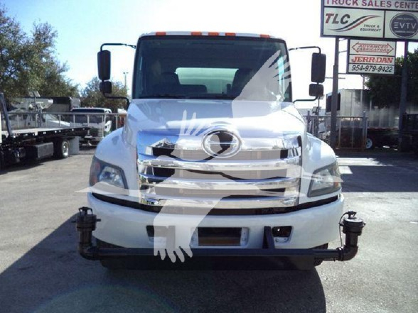 Front view of a white 2019 Hino 338 with a front bumper guard and chrome grille, dealership lot in background.