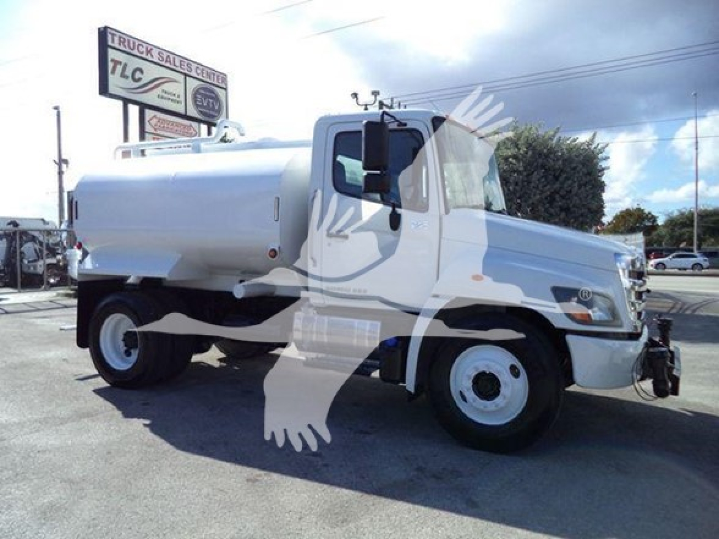 2019 Hino 338 medium-duty tank truck in a dealership lot, white cab and tank with black tires, side view with front grille and bumper visible