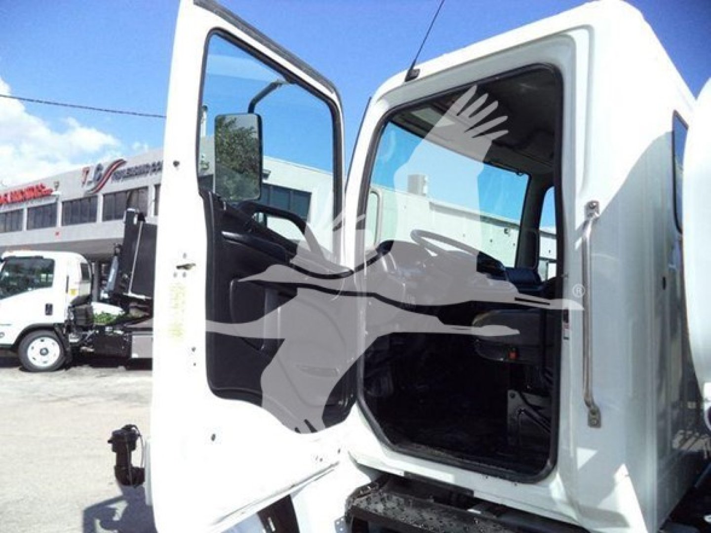 Truck cab interior with open door showing driver's seat and dashboard in a white 2019 Hino 338.