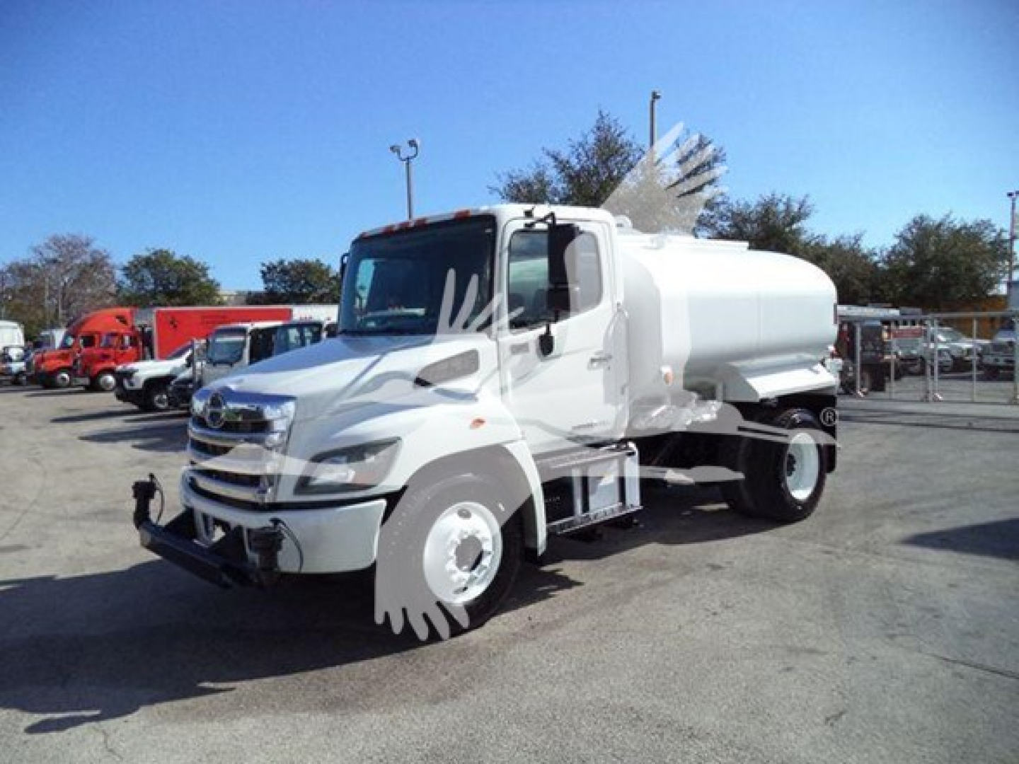 Hino 338 truck with tanker body in a dealership lot showing cab and tank.