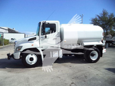 Truck cab and tank body of a 2019 Hino 338 with a cylindrical white tank mounted behind the cab, side view showing single rear wheels, no visible text