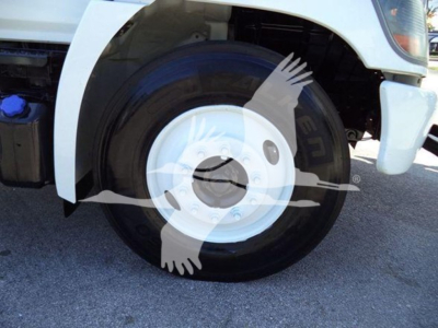 Truck wheel and fender of a 2019 Hino 338 showing front wheel, white rims, and partial body panel.