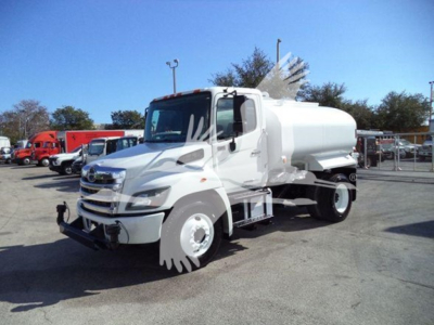 Hino 338 truck with tanker body in a dealership lot showing cab and tank.
