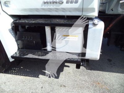 Truck side view showing steps and fuel tank with warning label and compartment doors. Partial badge reads 'HINO 338' on cab along with a warning label on the side panel.