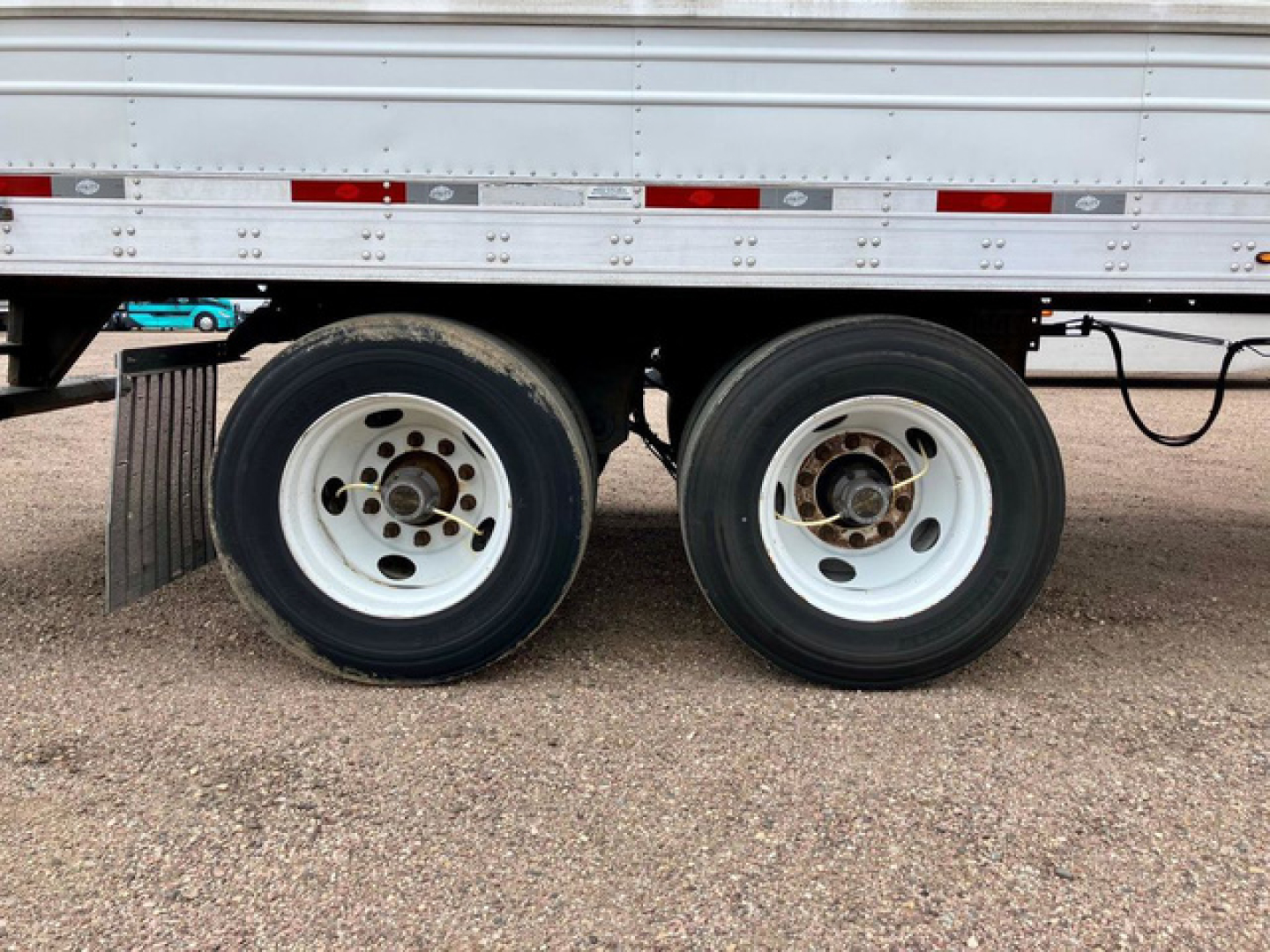 Dual rear axles of a 2022 Utility Reefer trailer showing white rims and black tires under a refrigerated trailer side panel.