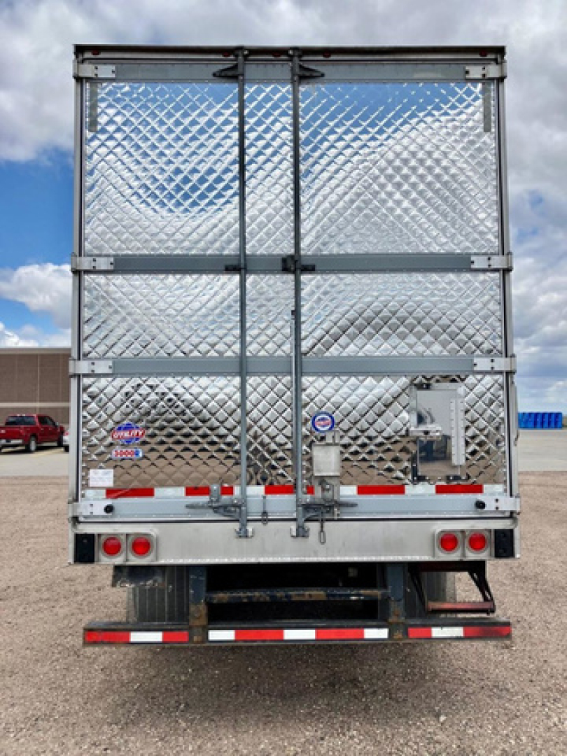 Refrigerated trailer back with diamond plate doors, vertical hinges, and rear lights. Stock tag and mechanical components visible near center-right.