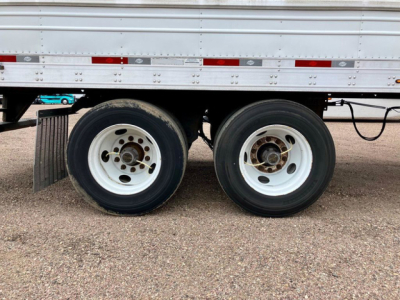 Dual rear axles of a 2022 Utility Reefer trailer showing white rims and black tires under a refrigerated trailer side panel.