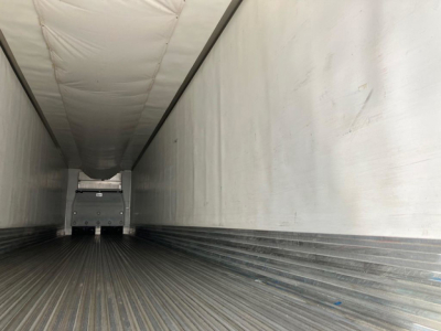 Trailer interior showing empty refrigerated trailer cargo area with ribbed floor and insulated white walls.
