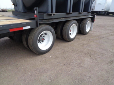 Demco Liquid Tender trailer wheel assembly showing dual wheels and a triple-axle configuration on a trailer bed.