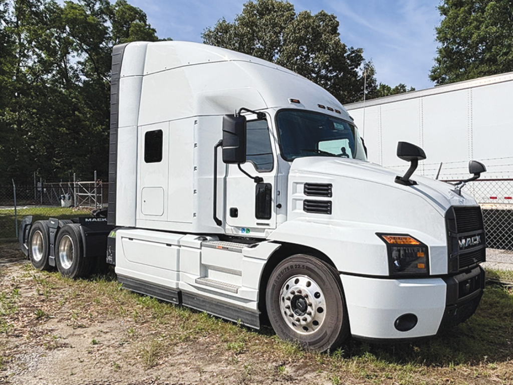 Mack Anthem sleeper truck with white exterior and extended cab, side view showing front grille, headlights, and dual rear axles, VIN tag not visible.