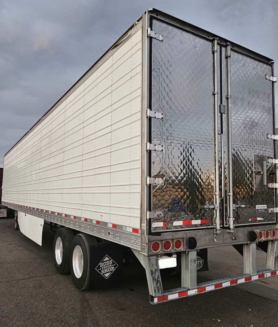 Trailer rear and side view showing cargo trailer with white paneled walls and diamond plate rear doors.