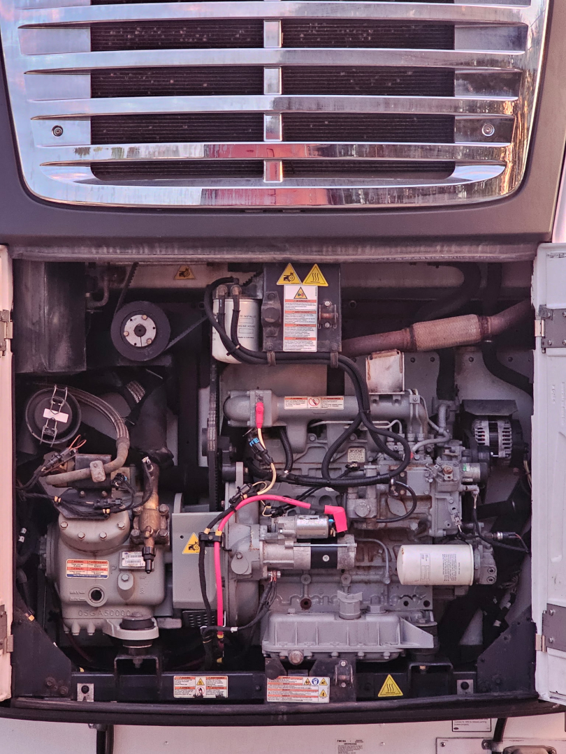 Engine compartment of a Hyundai ThermoTech TL reefer trailer showing diesel engine with hoses, belts, and warning labels.