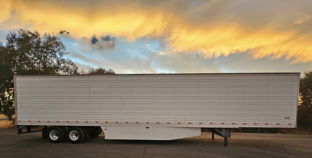Trailer side view showing a white Hyundai ThermoTech TL reefer trailer with dual rear axles under a sunset sky.