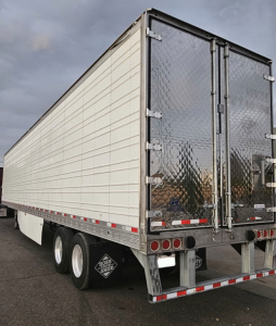 Trailer rear and side view showing cargo trailer with white paneled walls and diamond plate rear doors.