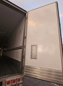 Trailer rear door open showing interior of reefer trailer with metal ribbed floor and side walls
