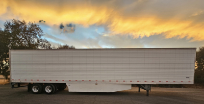 Trailer side view showing a white Hyundai ThermoTech TL reefer trailer with dual rear axles under a sunset sky.