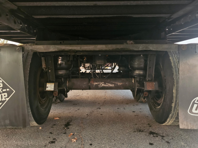 Trailer undercarriage showing axles, suspension, and dual wheels of a reefer trailer. Visible components include leaf springs, axles, and undercarriage frame.