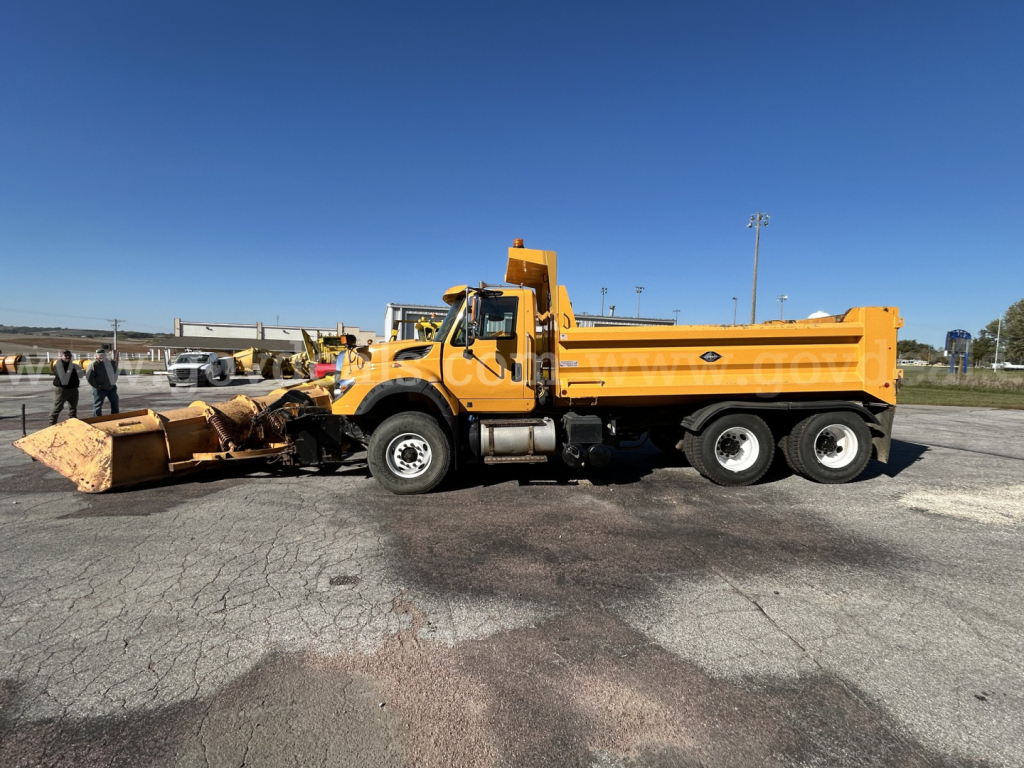 Truck-mounted snow plow truck with yellow dump bed, International WorkStar 7600, side view showing plow attachment and cab.