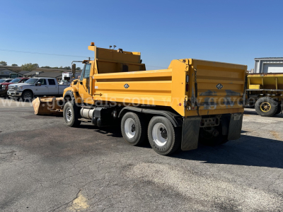 Yellow International WorkStar 7600 dump truck with plow setup, side view showing rear duals and cargo bed, VIN plate not visible.