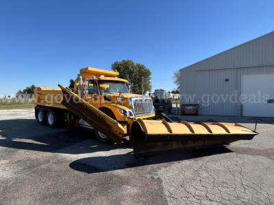 International WorkStar 7600 6x4 plow truck with large front plow and dump bed, yellow paint, VIN and stock numbers not visible on image