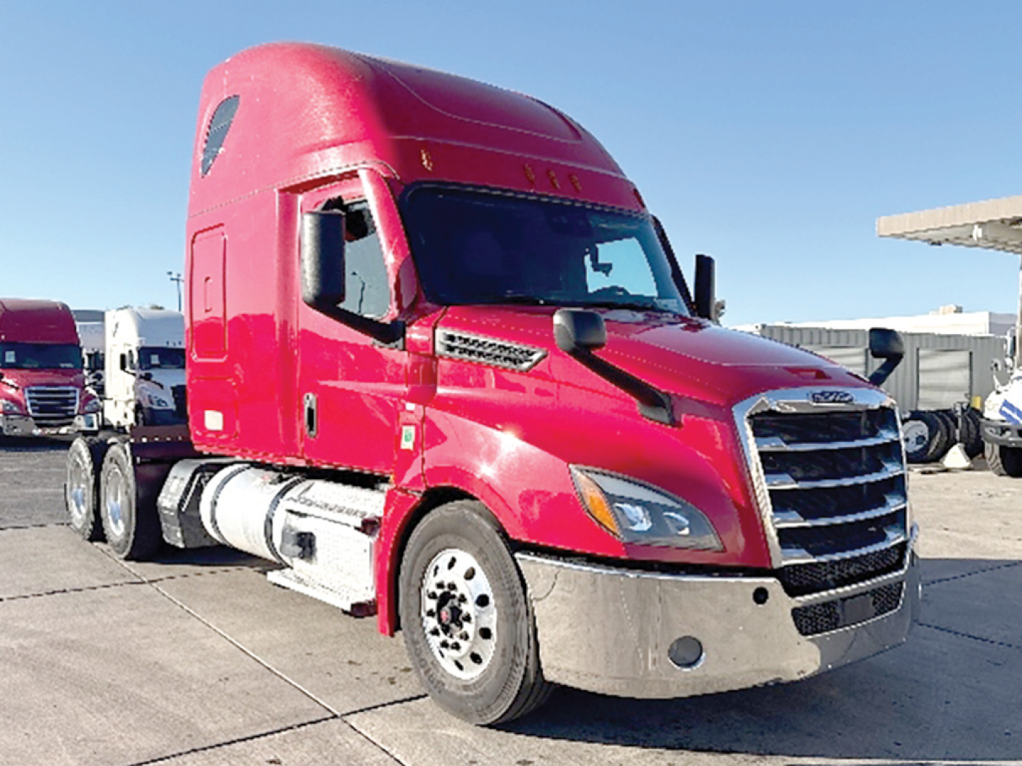Freightliner Cascadia 126 tractor in magenta/red color, front cab view with silver bumper, large grille, and dual fuel tanks on the side.