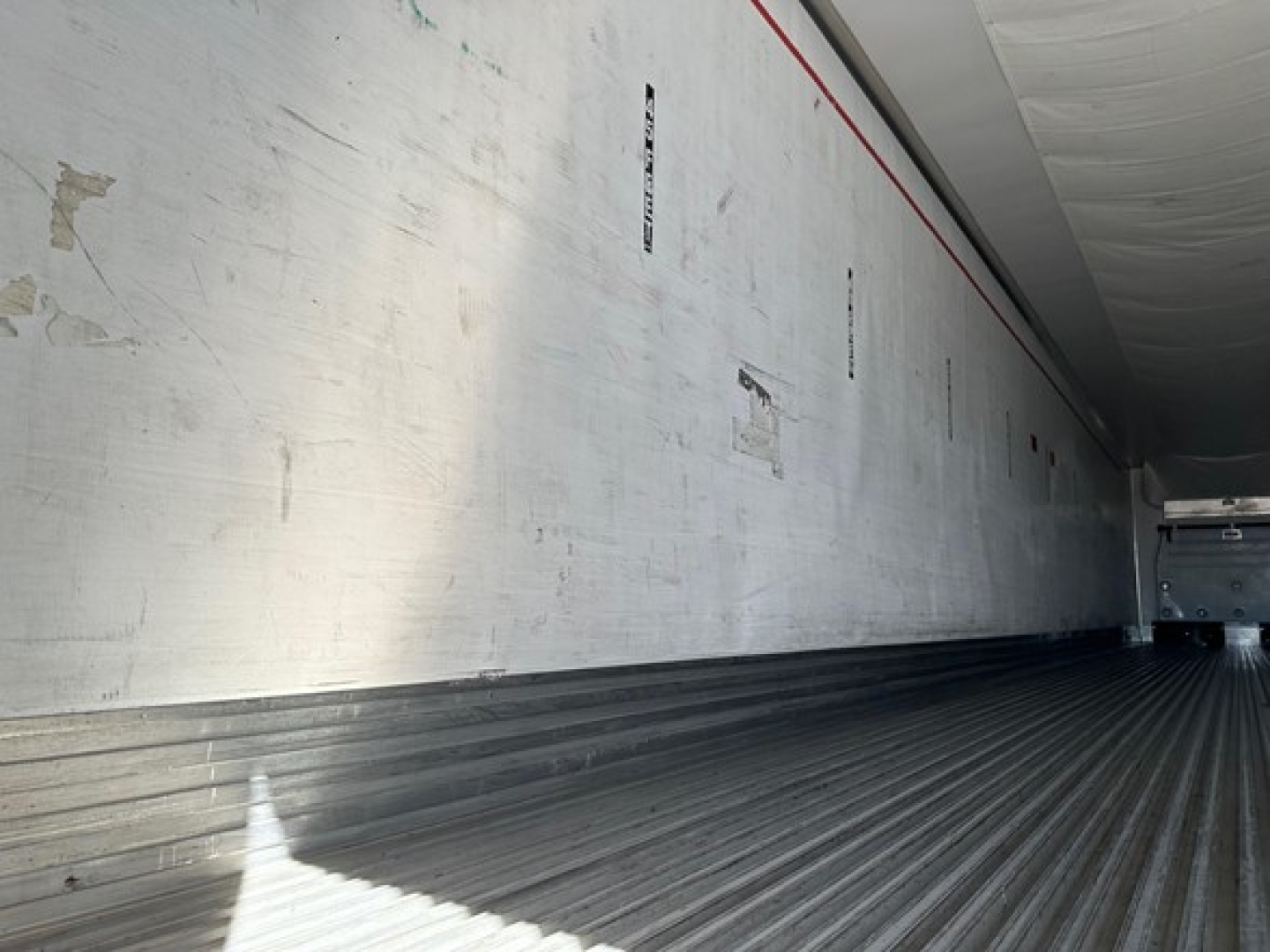 Trailer interior showing aluminum sidewalls with vertical stamps and a ribbed floor, empty cargo area.
