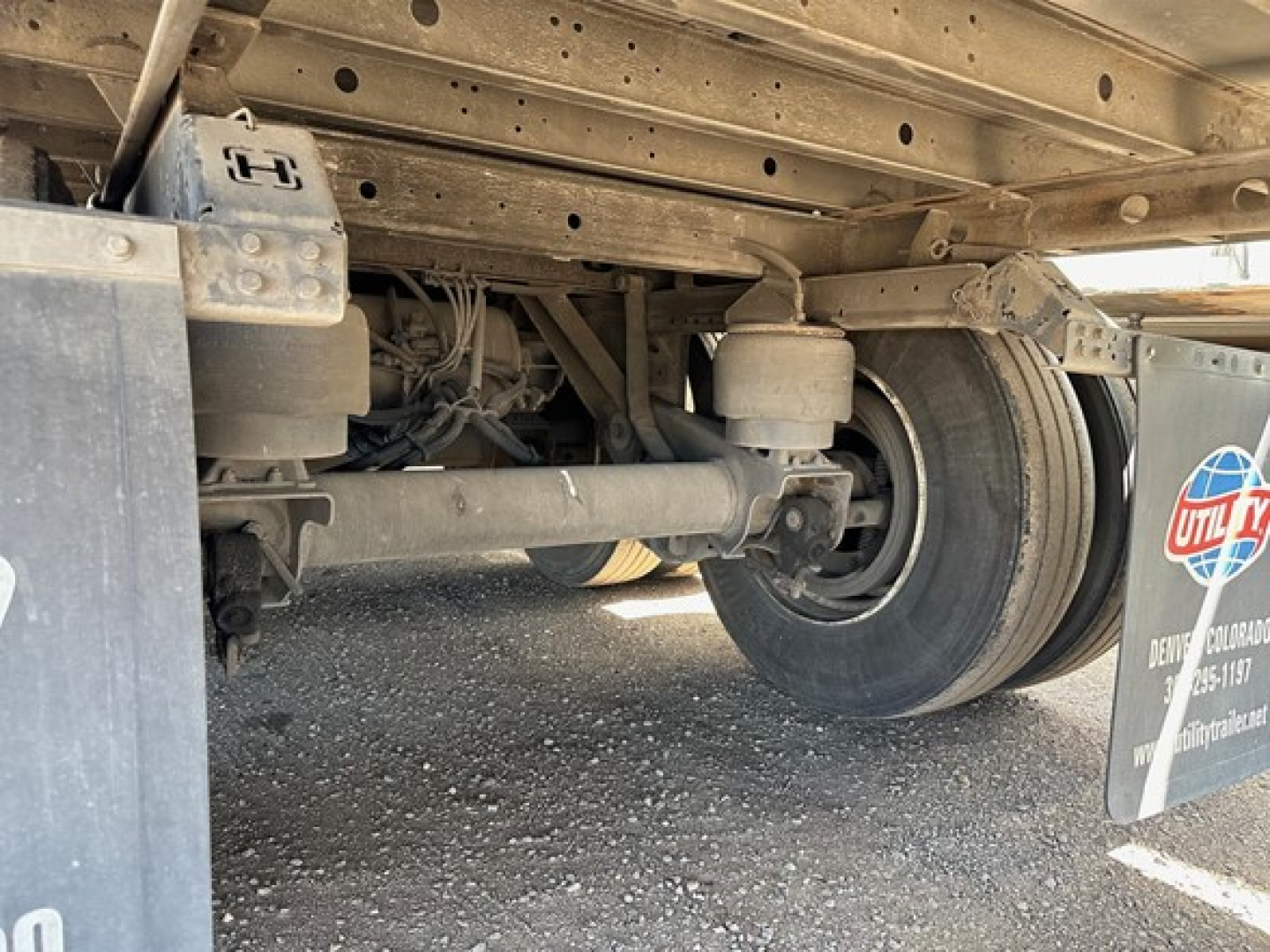 Underbody of a 2017 Utility 3000R trailer showing rear axle, suspension, and components; visible wheel, leaf spring, and frame members.