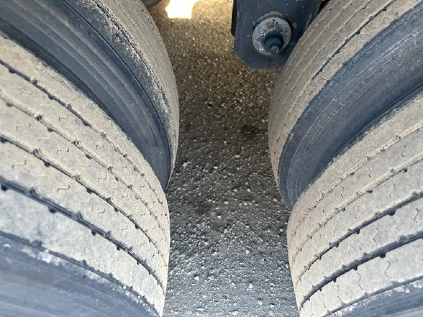 Rear view of a Utility 3000R trailer with dual axles showing worn tires and undercarriage components.