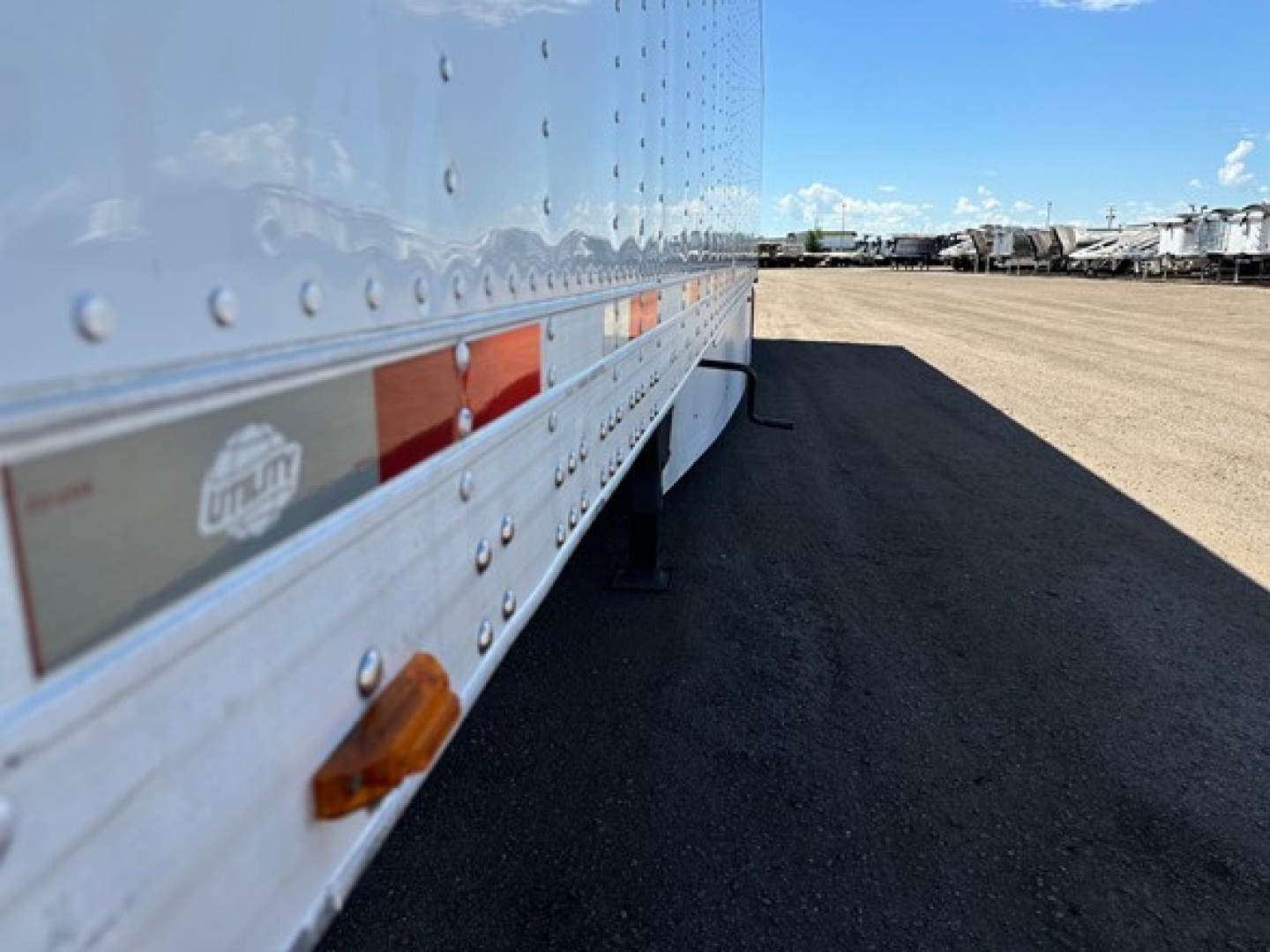 Trailer side of a Utility 3000R reefer with riveted aluminum side, reflective stripes, and clearance lights.