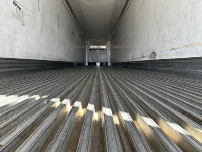 Trailer interior cargo area showing ribbed flooring and sidewalls, rear opening horizon visible in distance.