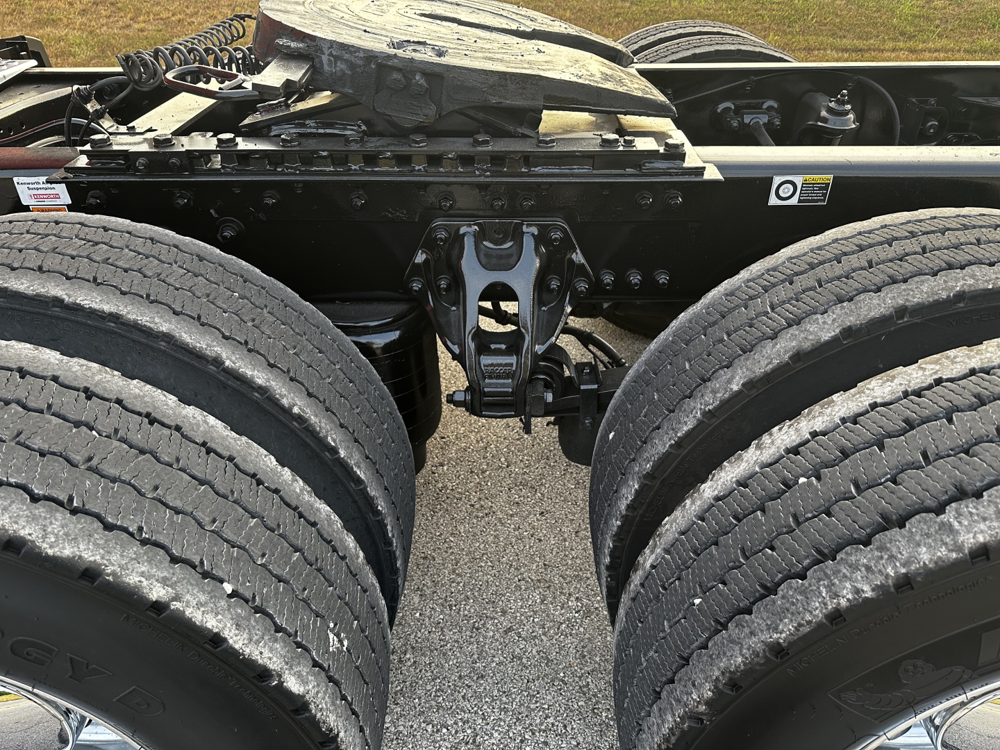 Kenworth T680 chassis center view showing dual rear dual tires and fifth wheel hitch area with drive line and frame rails.