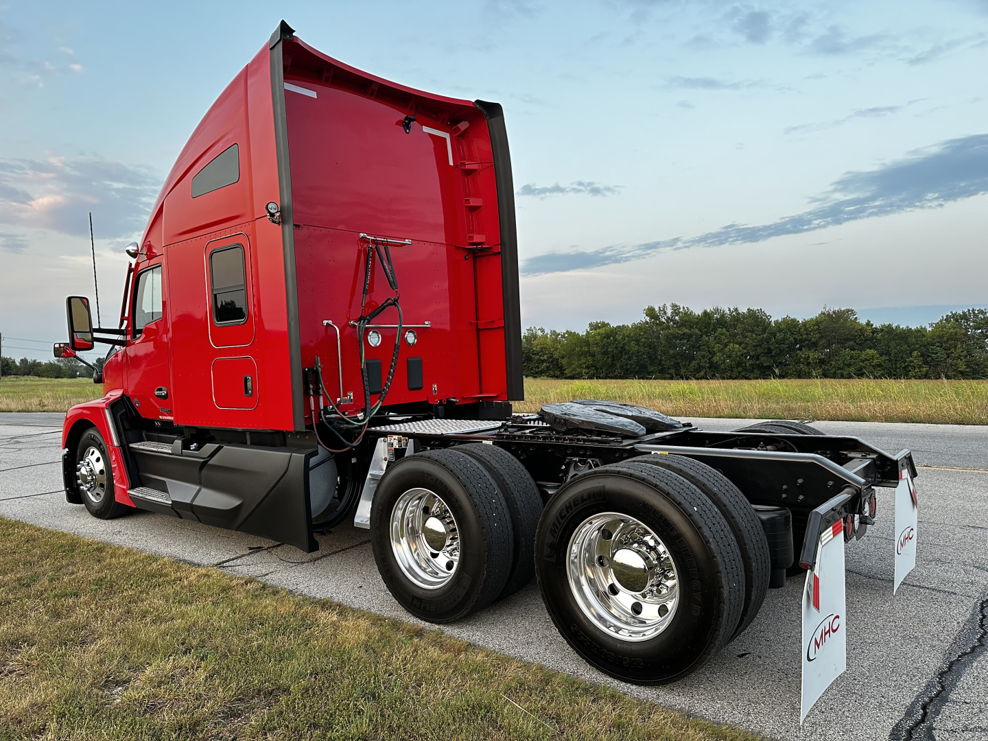 Kenworth T680 semi truck cab and chassis showing red sleeper cab and dual rear axles with chrome wheels.